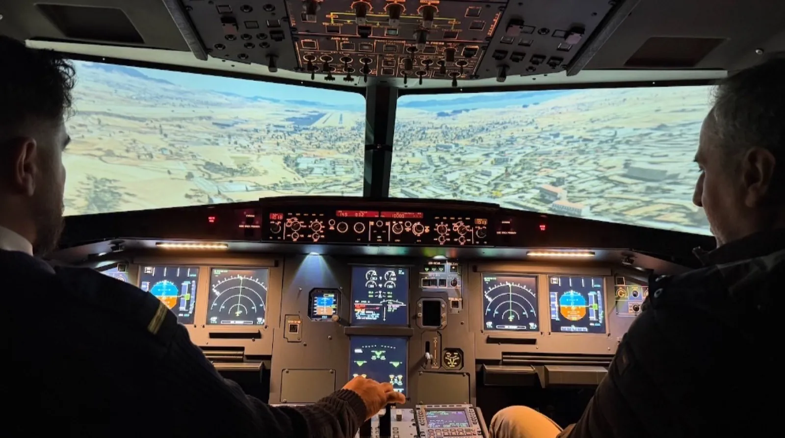 Two pilots flying an A320 flight simulator with the visual system running